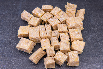 Close up of tempeh cut into small cube pieces. Tempeh is made from fermented soybeans is a popular meat substitute. It originated in Indonesia. Vegan foods. Plant protein food.