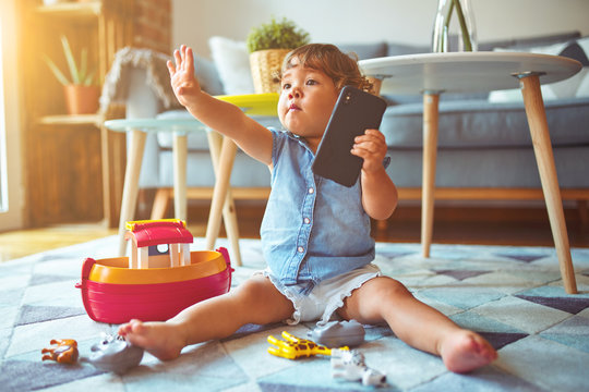 Beautiful toddler child girl sitting on the carpet playing with smartphone