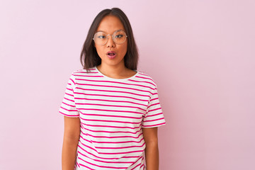 Fototapeta premium Young chinese woman wearing striped t-shirt and glasses over isolated pink background afraid and shocked with surprise expression, fear and excited face.