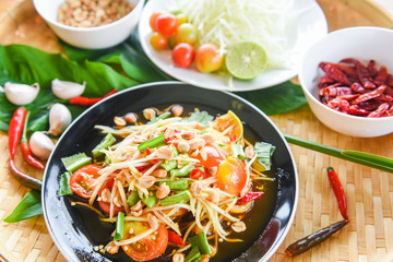 Papaya salad on black plate / Close up of green papaya salad spicy thai food and ingredients on the table