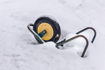 Winter, snow, wheelbarrow in the garden. Garden car in the snow. Cart for the garden in the winter...