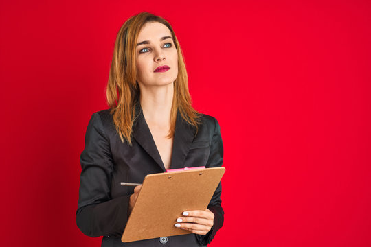 Young beautiful redhead businesswoman wearing suit writing on flip board