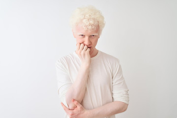 Young albino blond man wearing casual t-shirt standing over isolated white background looking stressed and nervous with hands on mouth biting nails. Anxiety problem. - obrazy, fototapety, plakaty