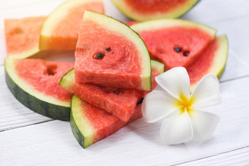 Fresh watermelon on wooden background - pile of red watermelon slices and white flower