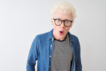 Young albino blond man wearing denim shirt and glasses over isolated white background afraid and...