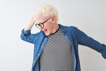 Young albino blond man wearing denim shirt and glasses over isolated white background Dancing happy and cheerful, smiling moving casual and confident listening to music