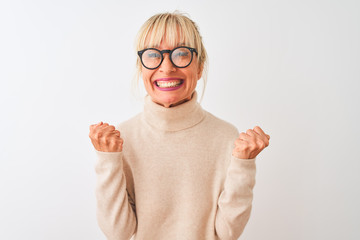Middle age woman wearing turtleneck sweater and glasses over isolated white background celebrating...