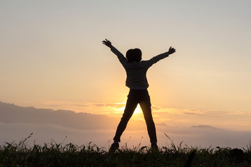 Silhouette of happy child jumping playing on mountain at sunset or sunrise