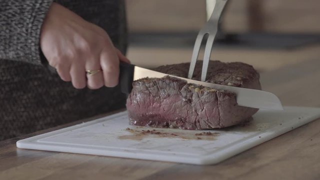 Femme coupe un r&ocirc;ti de b&oelig;uf dans une cuisine.