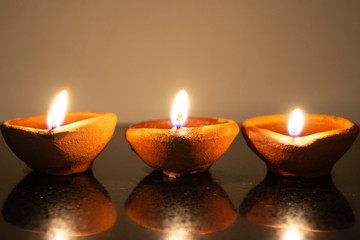 Diwali diyas lined up in low light on a reflective surface