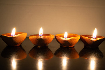 Diwali diyas lined up in a row on a reflective surface