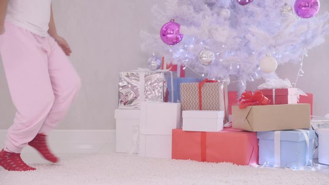 Curious little girl comes unnoticed to christmas tree at night, opens a present box, magic light illuminates from inside, kid ascertains that nobody sees her, closes the box and puts it back.