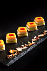 Colored marmalade, laid out in a beautiful line on a black plate. food background. Fusion food concept, low key, copy space.