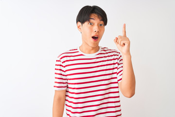 Young chinese man wearing casual striped t-shirt standing over isolated white background pointing finger up with successful idea. Exited and happy. Number one.