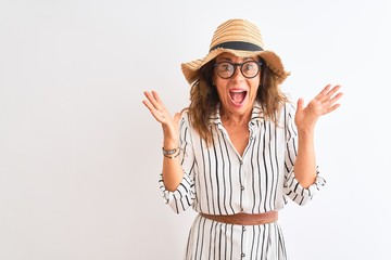 Obraz na płótnie Canvas Middle age businesswoman wearing striped dress glasses hat over isolated white background very happy and excited, winner expression celebrating victory screaming with big smile and raised hands