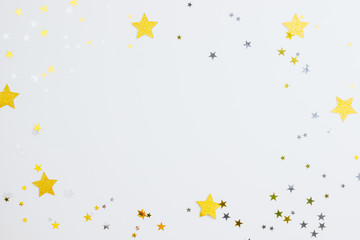 Frame with space for text made of golden stars confetti on white background. Flat lay, top view. Minimal background.