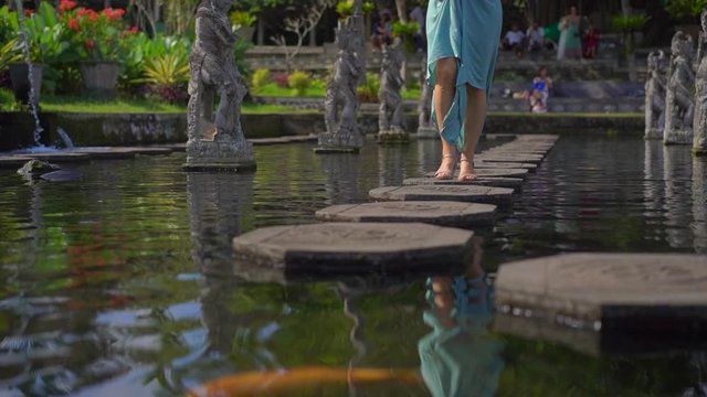Slowmotion shot of a young woman tourist visiting the Tirta Gangga water palace, former royal palace on the Bali Island, Indonesia