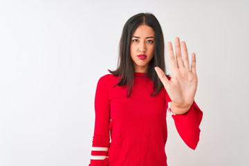 Young beautiful chinese woman wearing red dress standing over isolated white background doing stop sing with palm of the hand. Warning expression with negative and serious gesture on the face.