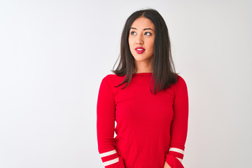 Young beautiful chinese woman wearing red dress standing over isolated white background smiling looking to the side and staring away thinking.