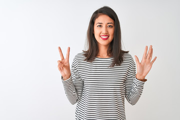 Young beautiful chinese woman wearing striped t-shirt standing over isolated white background showing and pointing up with fingers number seven while smiling confident and happy.