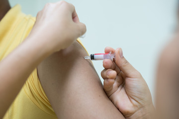 Close up doctor's hand injecting for vaccine in the shoulder woman patient.Nurse using syringe are vaccination to patient for influenza protection.Medication treatment concept.