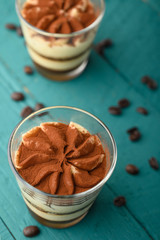 flat lay, Tiramisu two glasses with coffee grains on a green wooden background. vertical photo