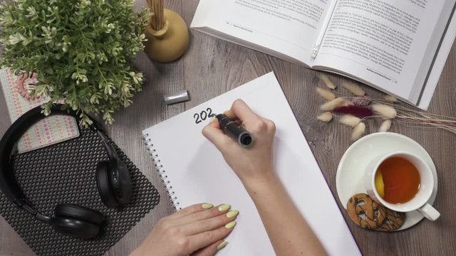 View on hands from top: Girl writes bucket list on new 2020 year