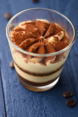 Tiramisu two glasses with coffee grains on a blue wooden background.Vertical photo