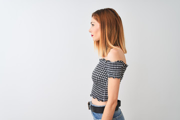 Beautiful redhead woman wearing casual t-shirt standing over isolated white background looking to side, relax profile pose with natural face with confident smile.