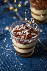 Tiramisu in a glass sprinkled with coconut. On a background of blurry lights