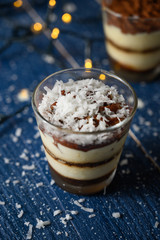 Tiramisu in a glass sprinkled with coconut. On a background of blurry lights