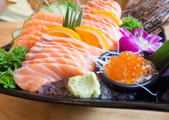 Big set of sushi on a wooden table in a Japanese restaurant.Fresh salmon sliced for sushi menu.