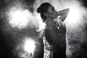 B&W dark tone of Erotic silhouette nice shape Asian woman in Lace see through evening gown splatter with many studio lighting as back rim light with dent puff smoke to show sensual sexy posing