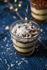 Tiramisu in a glass sprinkled with coconut. On a background of blurry lights