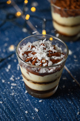 Tiramisu in a glass sprinkled with coconut. On a background of blurry lights