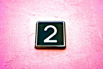 Black number two, 2, on bright pink vigneted background.