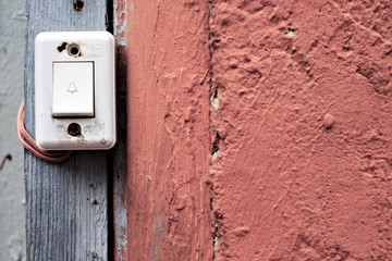 Old defunct door bell button with a door bell sign and electric wires.