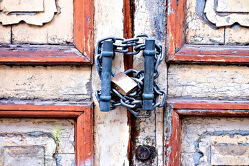 Very old very dirty and grungy closed door with chain and padlock.