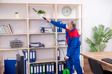 Old professional contractor doing pest control in the office