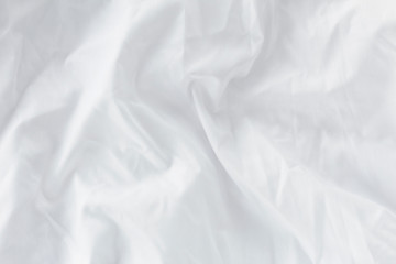 Bed, white wrinkles bedding sheets. Light cozy background with copy space. Flat lay, top view. 