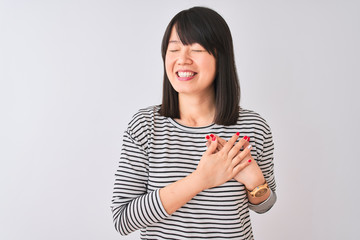 Obraz premium Young beautiful chinese woman wearing black striped t-shirt over isolated white background smiling with hands on chest with closed eyes and grateful gesture on face. Health concept.