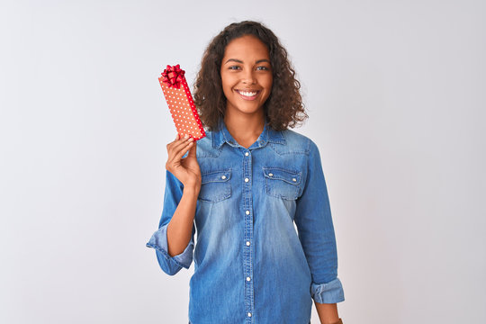Young brazilian woman holding valentine gift standing over isolated white background with a happy face standing and smiling with a confident smile showing teeth