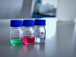 Bottles and blue cap with green, red and clear solution buffer pH 4, 7 and 10 on bench laboratory for analysis and calibrate the instrument. Blur background, has space can use for science background.