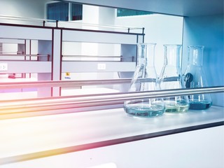 Erlenmeyer flasks on shelf in chemistry laboratory with blue solvent indicator, titration water...