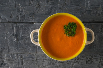 Parsley leaves in a bowl with cream of pepper soup on a wooden table. Flat lay.