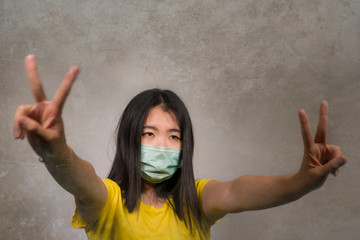 Young beautiful pacifist Asian Korean woman in face mask doing peace fingers symbol standing for human rights respect and freedom in anti violence protest against abuse