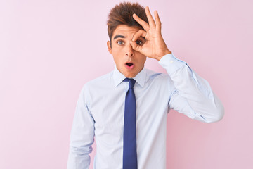 Young handsome businessman wearing shirt and tie standing over isolated pink background doing ok gesture shocked with surprised face, eye looking through fingers. Unbelieving expression.