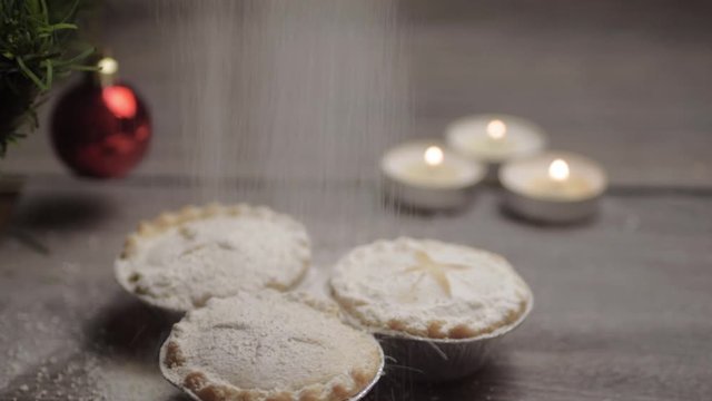 Sprinkling icing sugar finishing touch over mince pies at Christmas