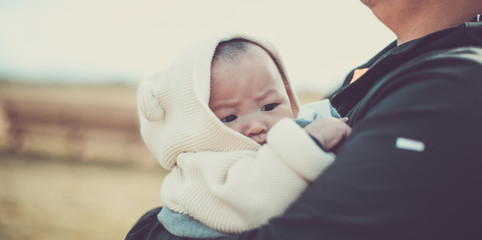 Asian baby in dads arms at the pumpkin patch