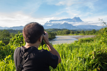 Asia Photographer man taking picture of beautiful Mount Kinabalu, Sabah, Borneo with nature environment 